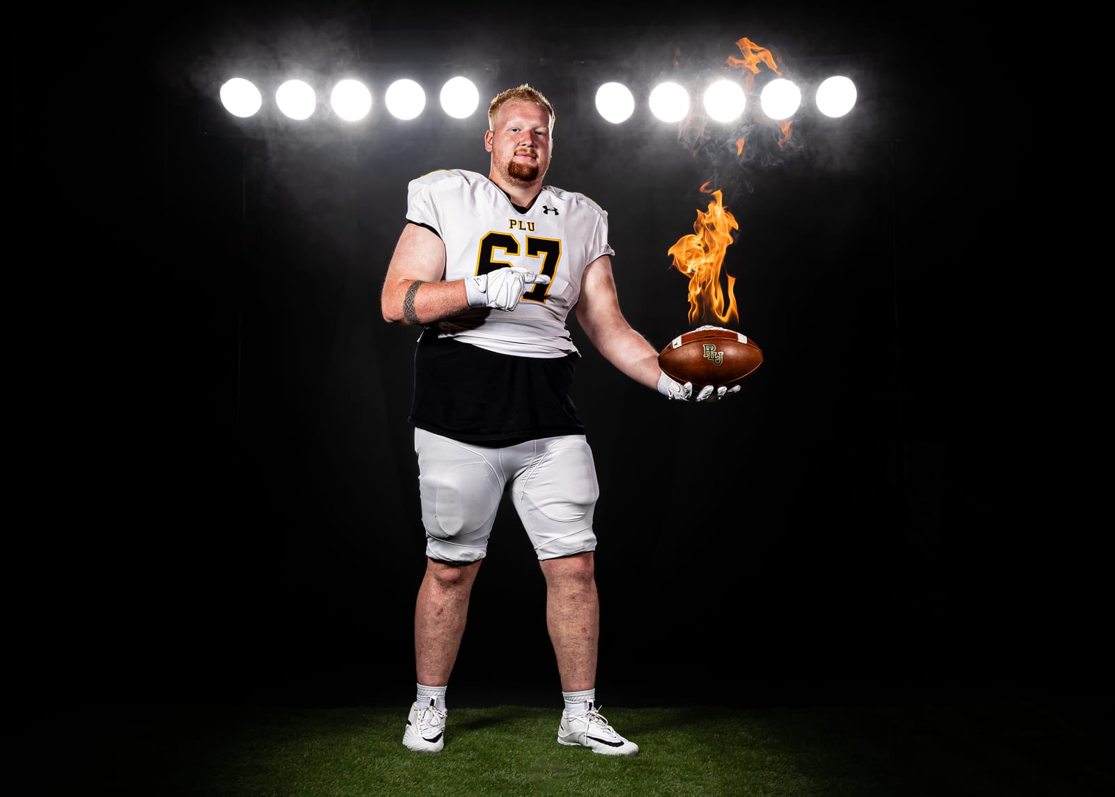 PLU football lineman holding a flaming football on media day