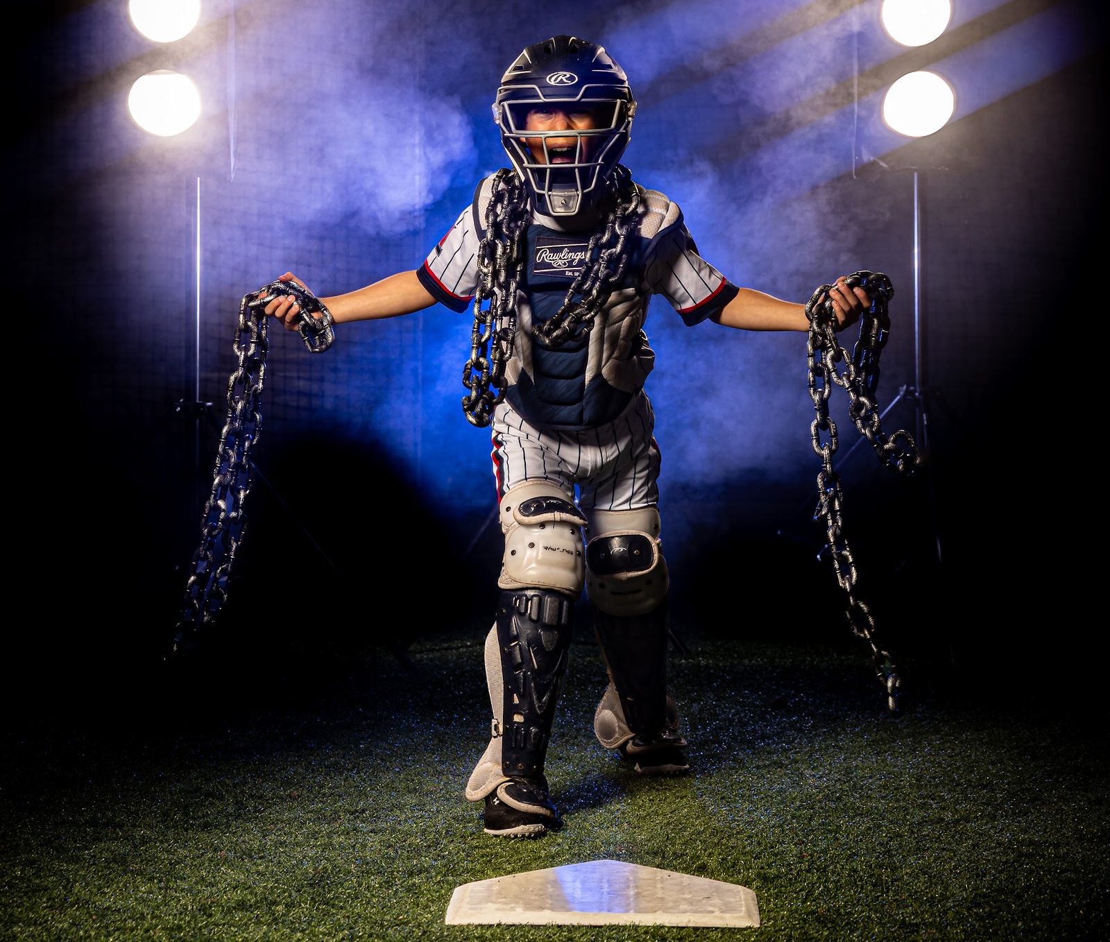 Young baseball catcher posed with chains under studio smoke