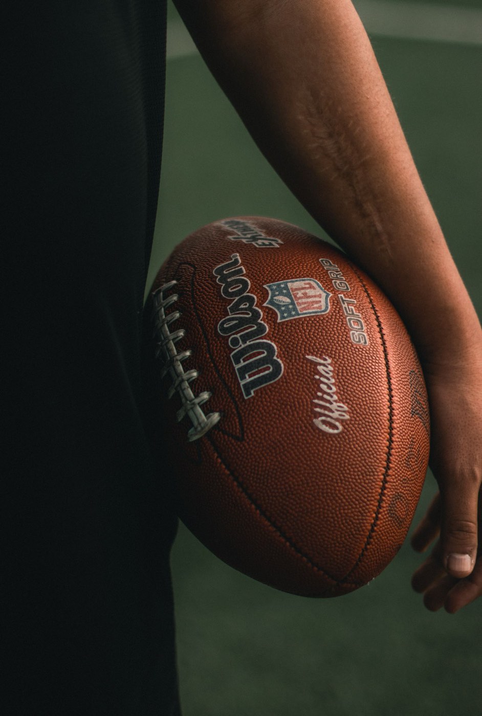 A football held at the hip in the dark